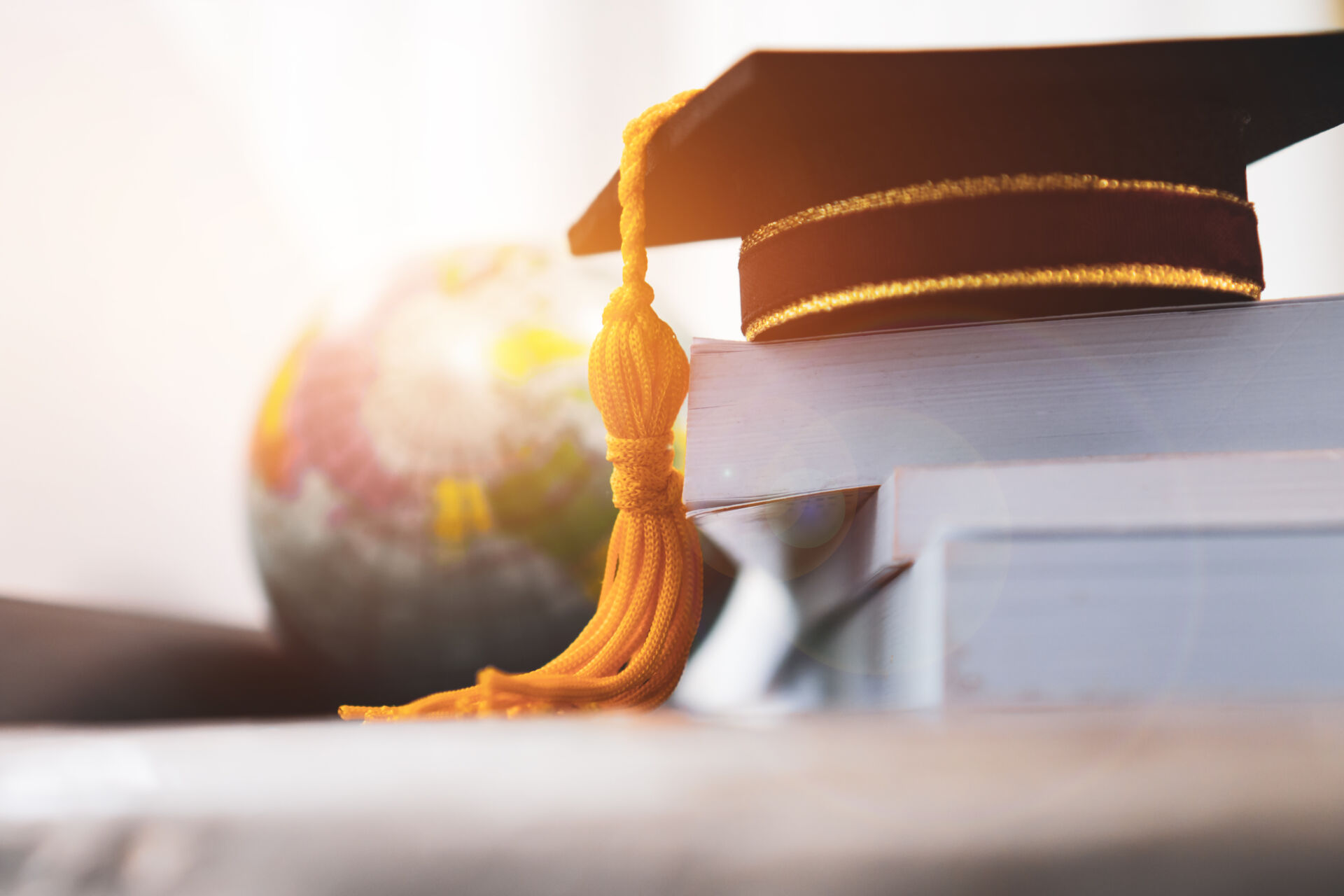 Mortarboard on stack of books, globe in background