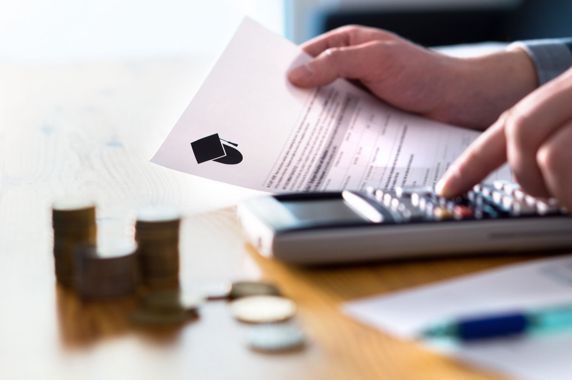 Person counting college savings fund, tuition fee or student loan with calculator. Education price and expenses concept. Money and papers on table.