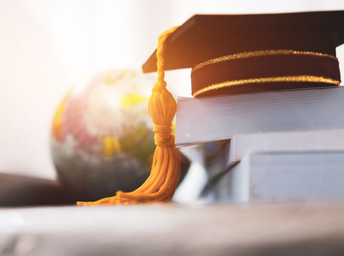 Mortarboard on stack of books, globe in background