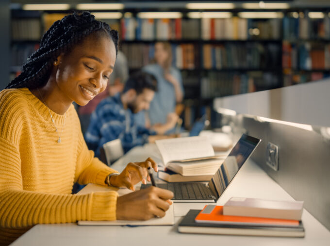 Student in a yellow sweatshirt studying in the library.