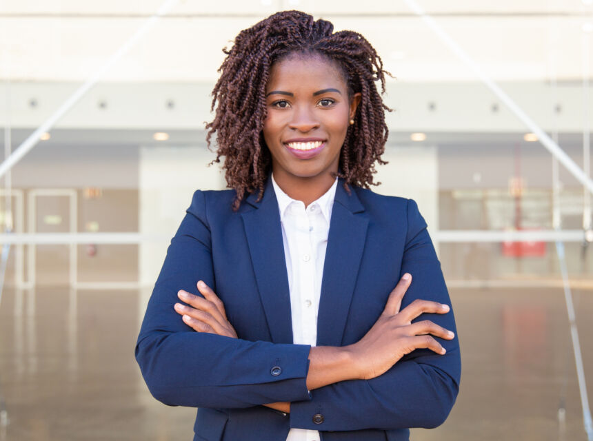 Professional woman, smiling, arms crossed, wearing a blue suit with a white collared shirt.